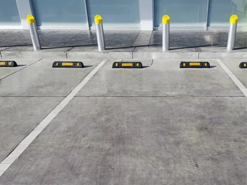 Commercial concrete flatwork with bollards and wheel stops at a business entrance