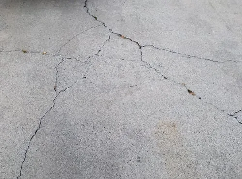 Concrete driveway surface with branching cracks indicating base failure
