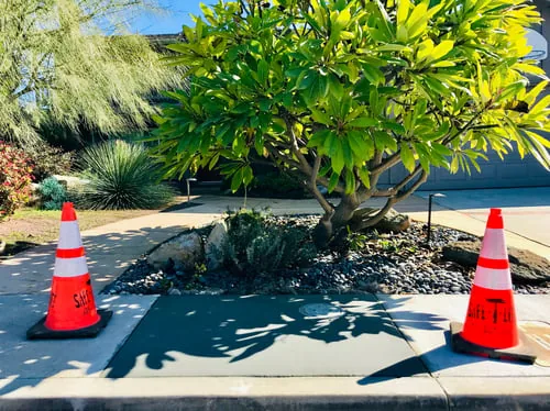 Newly poured and finished residential concrete driveway section with safety cones