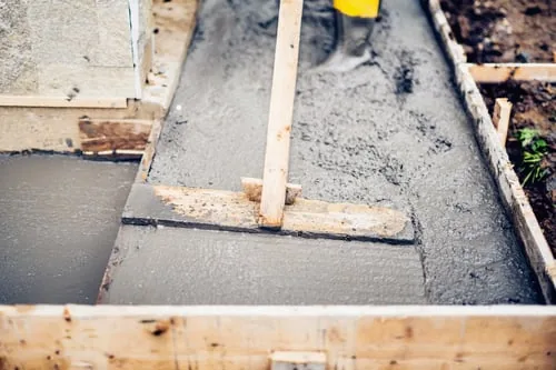 Concrete crew screeding a freshly poured slab between formwork on a Charlotte NC job site